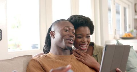 Joyful Couple Relaxing on Sofa with Tablet in Modern Living Room