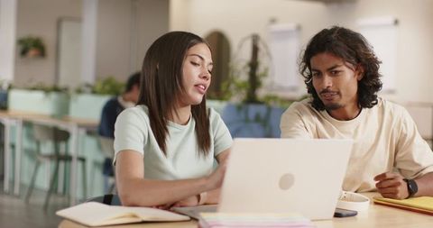 African American students collaborating on laptop in coworking study space with plants