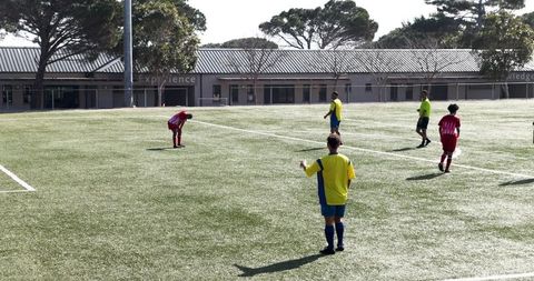 Youth soccer match with referee on bright sunny day