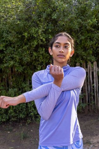 Woman in Lavender Activewear Stretching in Garden for Fitness Routine