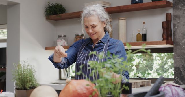 Senior Woman Cooking in Modern Kitchen, Smiling While Adding Seasoning - Download Free Stock Images Pikwizard.com