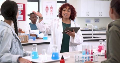 Diverse students learning science conducting experiments with teacher in lab