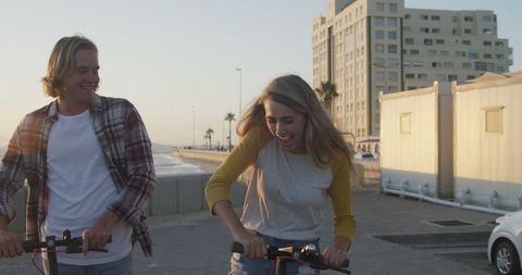 Joyful Couple Riding Electric Scooter at Beachfront Sunset