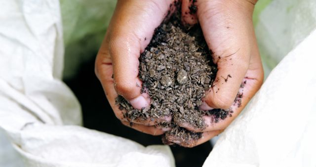 Close-up of child's hands holding rich, dark soil, emphasizing connection to nature and sustainable gardening. Ideal for use in educational content about agriculture, environmental awareness, organic farming, or promotional material for gardening products and eco-friendly practices.