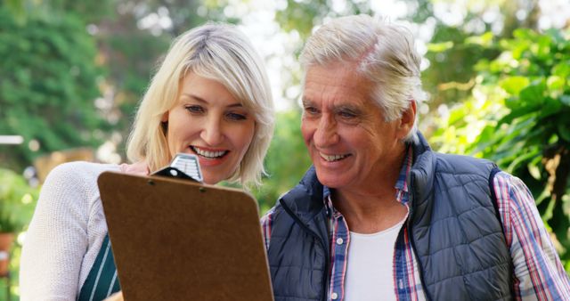 Mature couple looking at clipboard in greenhouse