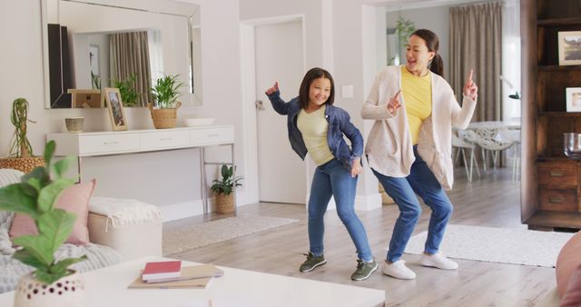 Image of happy asian mother and daughter dancing in living room. Family, motherhood, relations and spending quality time together concept digitally generated image.