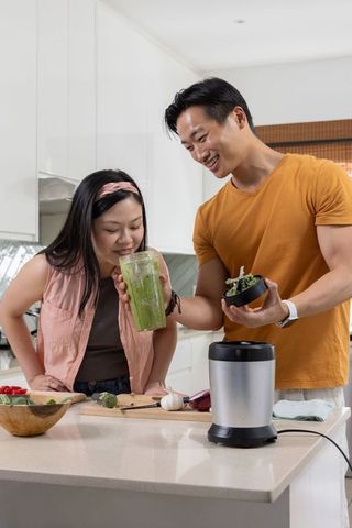 Couple making green smoothie in bright minimalist kitchen