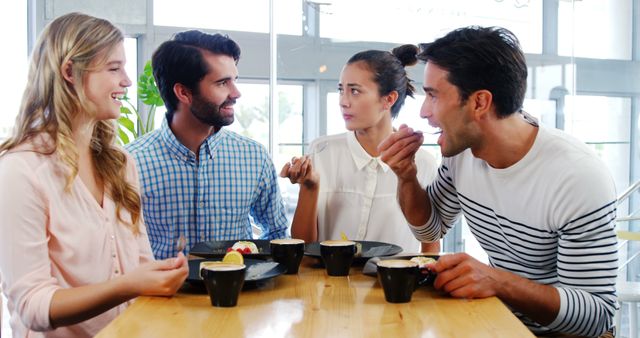 Four friends are gathered at a modern cafe, enjoying coffee and desserts while engaging in animated conversation. The scene conveys a sense of warmth and camaraderie as they share smiles and laughter. Useful for content related to cafe culture, social gatherings, friendship, leisure activities, and lifestyle promotions.