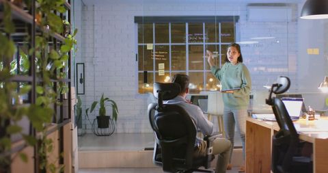 Businesswoman Presenting at Night Office Meeting