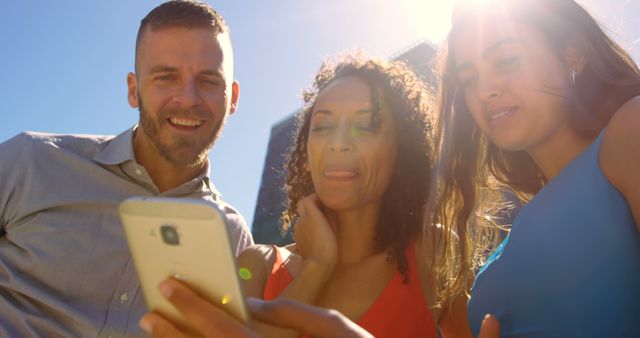 Three friends sharing and enjoying content on a smartphone outdoors - Download Free Stock Images Pikwizard.com