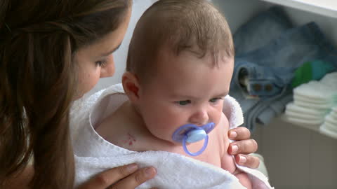 Mother Caring for Newborn with Pacifier at Home