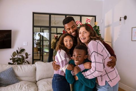Happy Family Embracing by Christmas Tree in Cozy Living Room