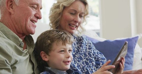 Cheerful Grandparents with Grandson Engaged with Tablet Device