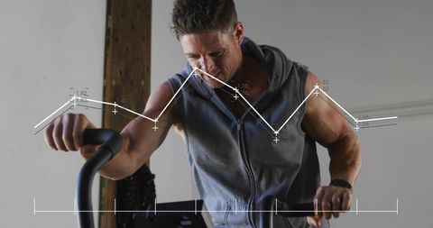 Mid-adult man pedaling indoor bike wearing zip-up hoodie and sports watch with data overlay