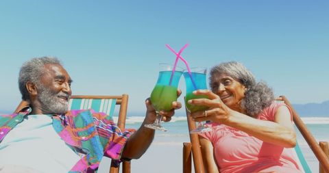 Senior African American Couple Toasting with Tropical Drinks at Beach