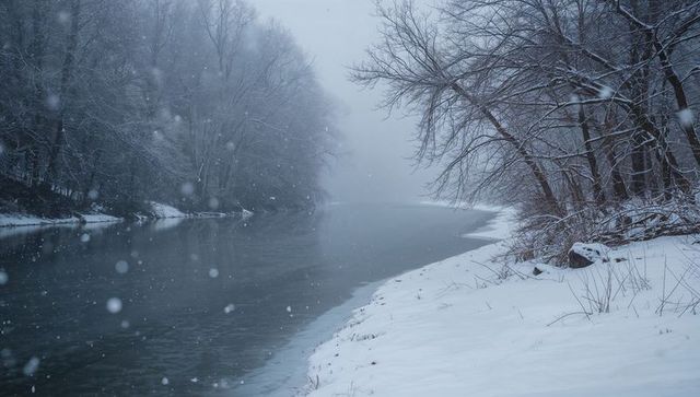 Misty winter riverbank with falling snowflakes, curving river channel through bare forest