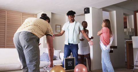 Friends celebrate new job with laughter and balloons at home