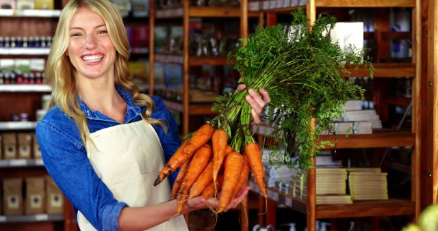 Portrait of smiling staff holding bunch of carrots in organic section of supermarket 4k