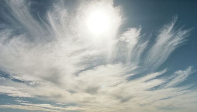 Radiant Sun and Wispy Cirrus Streaks over Expansive Blue Sky, Luminous Panoramic Background