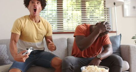 Excited Friends Gaming on Sofa with Popcorn
