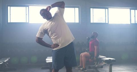 African men stretching and lifting weights indoor gym partners training and strength