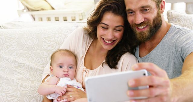 Happy Couple Taking Selfie with Baby on Couch - Download Free Stock Images Pikwizard.com