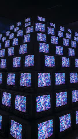 Pivoting Camera Showing Stacked CRT TVs Playing Neon Abstract Animation in Dark Gallery