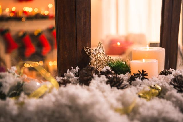 Perfect for holiday-themed promotions, greeting cards, and festive social media posts. Captures the warmth and coziness of Christmas with candles, star ornament, and snow-covered pine cones. Ideal for creating a festive atmosphere in advertisements or blog posts.