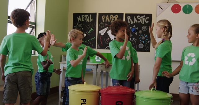 Diverse group of children, all wearing green recycling-themed t-shirts, actively participating in waste sorting activities in a classroom. Bins for metal, paper, and plastic are prominently displayed. Great for illustrating educational or environmental awareness programs geared towards children, promoting sustainability, and highlighting teamwork in educational settings.