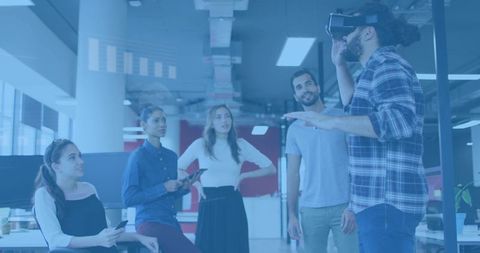 Startup team collaborating around virtual reality demo in modern open-plan office