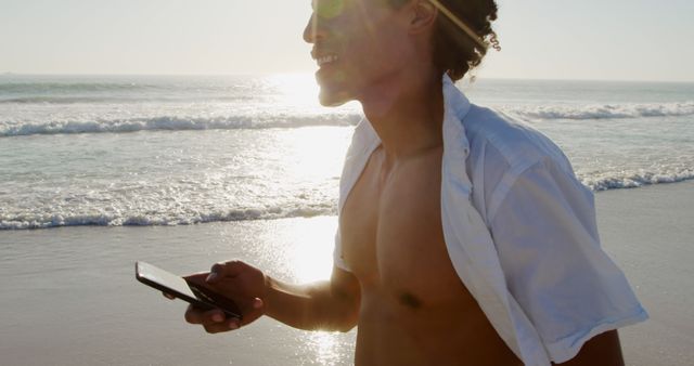 Carefree Young Man Walking on Beach Using Smartphone - Download Free Stock Images Pikwizard.com