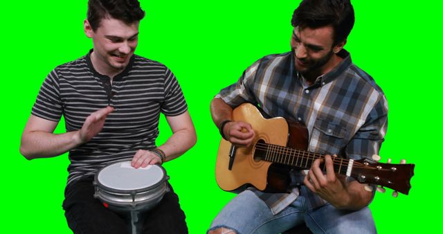 Male musicians playing guitar and drum against green screen