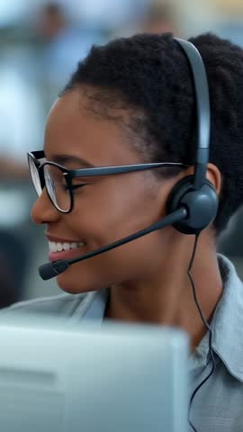 Vertical video Smiling call center agent answering incoming call with headset and computer
