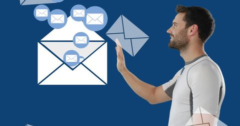 Smiling man engaging with floating email icons on blue background