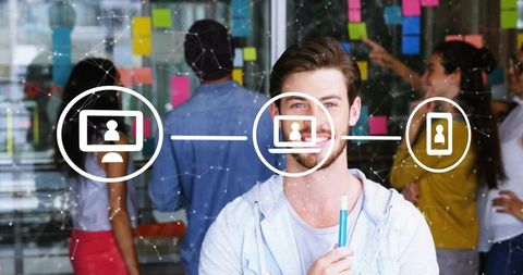 Young professional smiling holding marker near sticky notes and network icons for teamwork