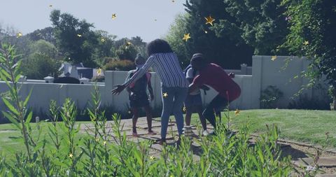Parents guiding children across garden stepping stones on sunny suburban lawn