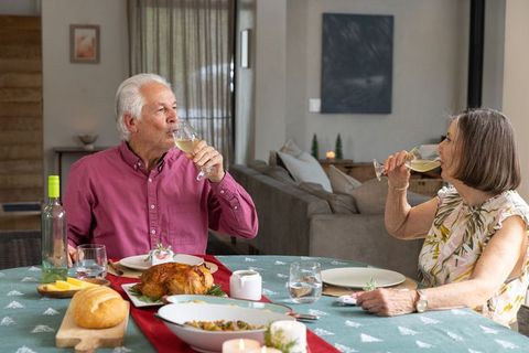 Senior couple enjoying festive meal with wine in cozy dining room