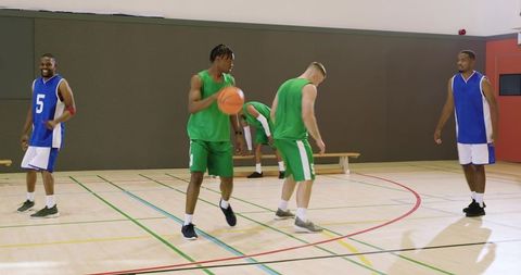 Indoor basketball team dribbling and chasing loose ball during fast break baseline drive