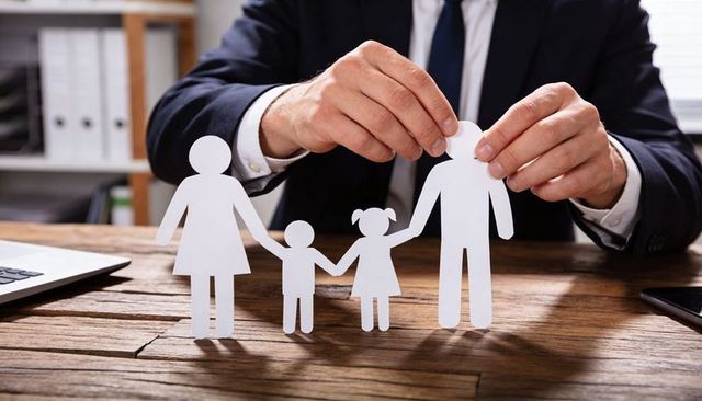 Businessman placing paper family cutouts on desk for family insurance protection and planning