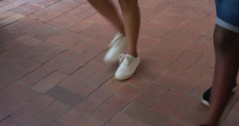 Casual summer walking on brick pavement with white sneakers and denim shorts, motion blur