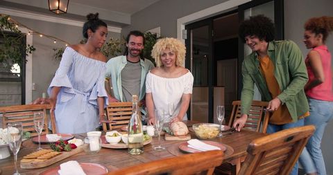 Group of Friends Preparing Table for Cozy Dinner Party