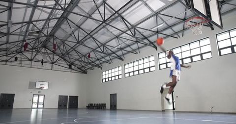 Basketball player dunking ball in gymnasium