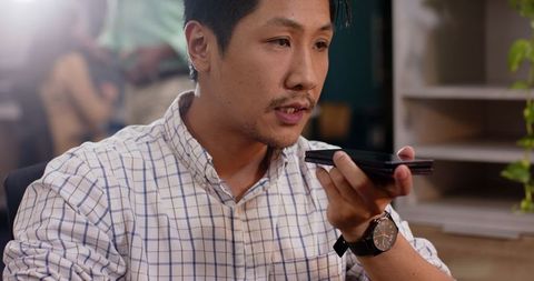 Professional man using smartphone voice command in modern office