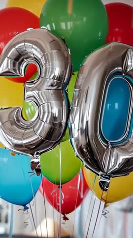 Vertical video showing silver 30 foil balloons floating among colorful latex party balloons