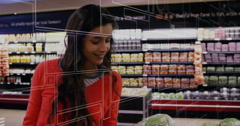 Smiling woman in red sweater inspecting lettuce while grocery shopping in produce aisle