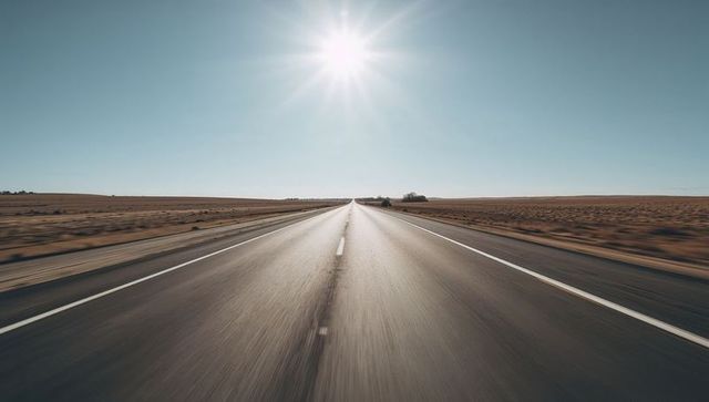 Sunlit highway stretching to horizon across flat rural plains with dramatic perspective