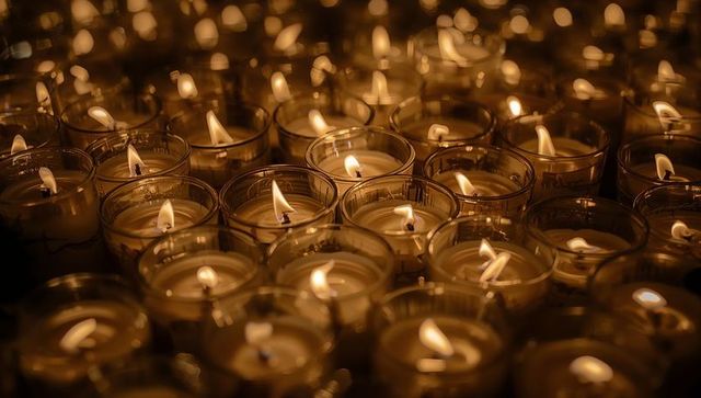 Glowing Votive Candles in Glass Holders Creating Warm Bokeh and Reflective Flame Pattern