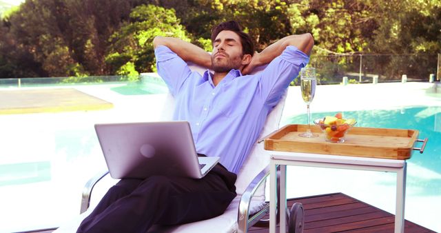 Businessman taking a break from work while lounging by a pool, with a laptop on his lap and a tray of refreshments nearby. Suitable for themes dealing with remote work, outdoor offices, luxury lifestyles, work-life balance, and leisure activities. Ideal for blog posts, articles, and advertisements in business, lifestyle, and travel industries.