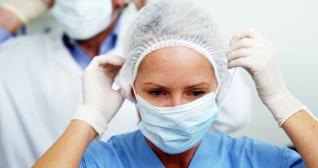 Medical staff wearing protective equipment including face masks and surgical caps in hospital. Suitable for illustrating themes related to healthcare, medical professions, hospital safety procedures, and risk management in clinical settings.