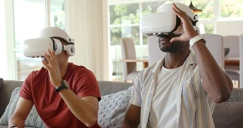 Diverse Friends Experiencing VR Headsets on Sofa in Bright Modern Living Room